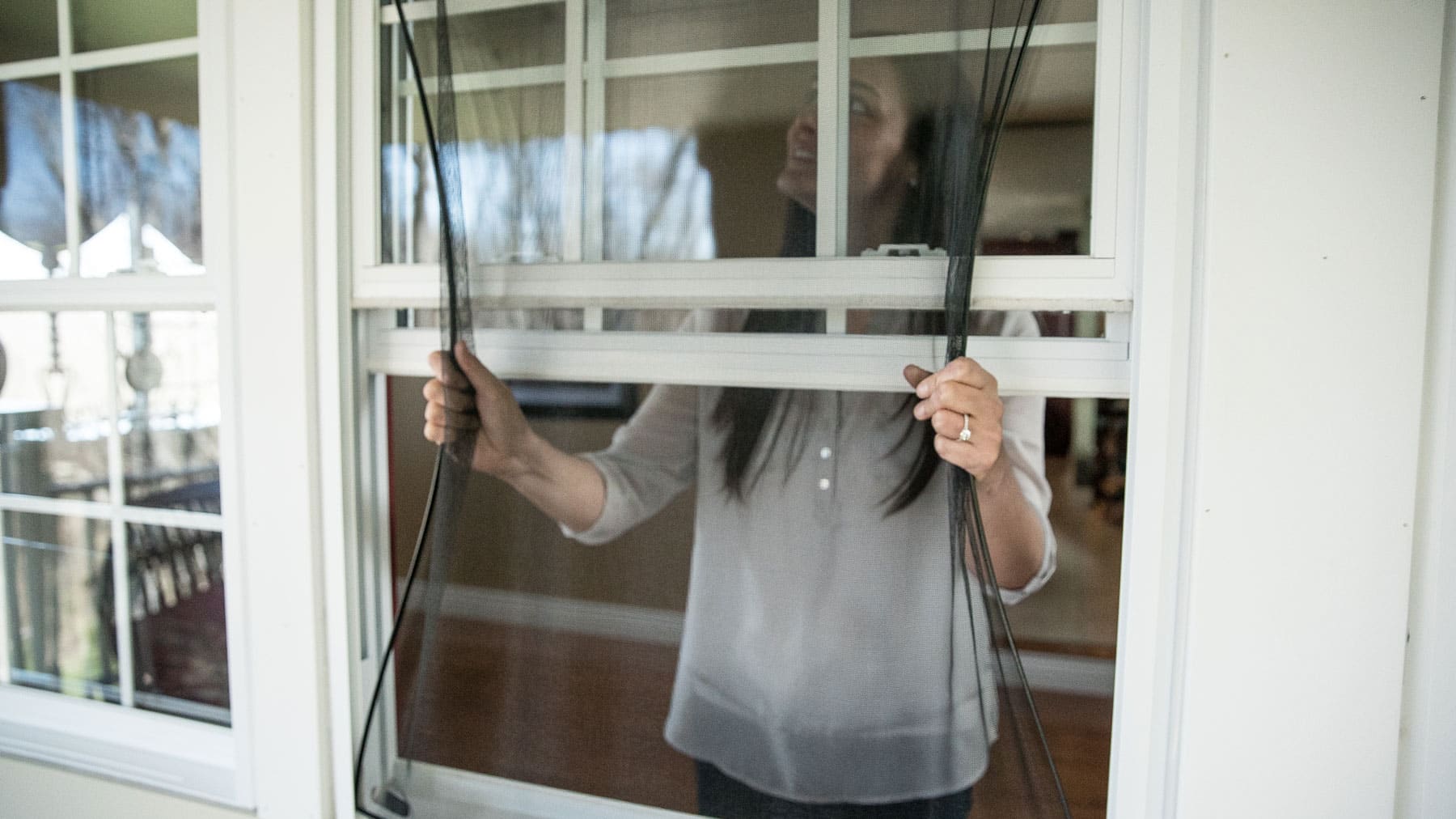 woman removing a flex screen from a window